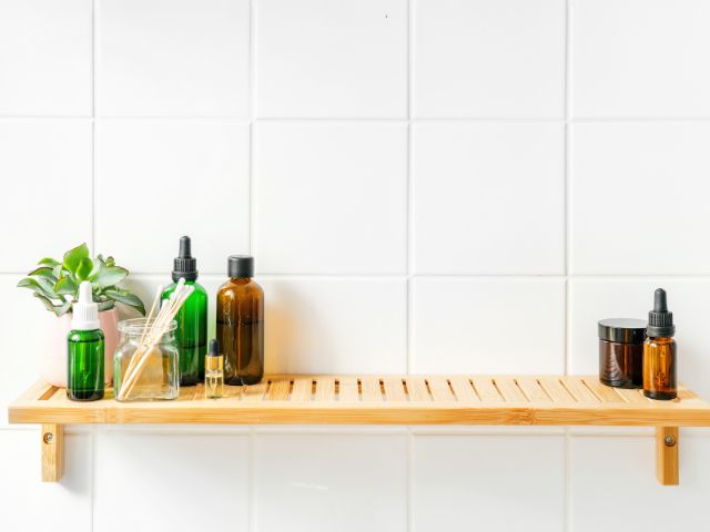 Eco friendly bathroom bamboo shelf with reusable bottles on it.