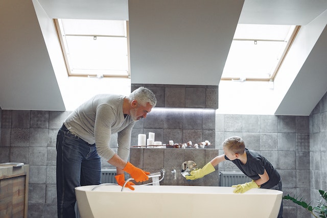 A father and son cleaning a bathroom thoroughly.