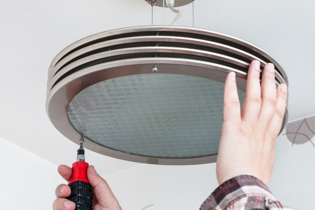 Electrician installing a round ceiling light.