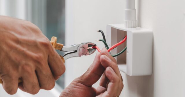 An electrician repairing a wall outlet.