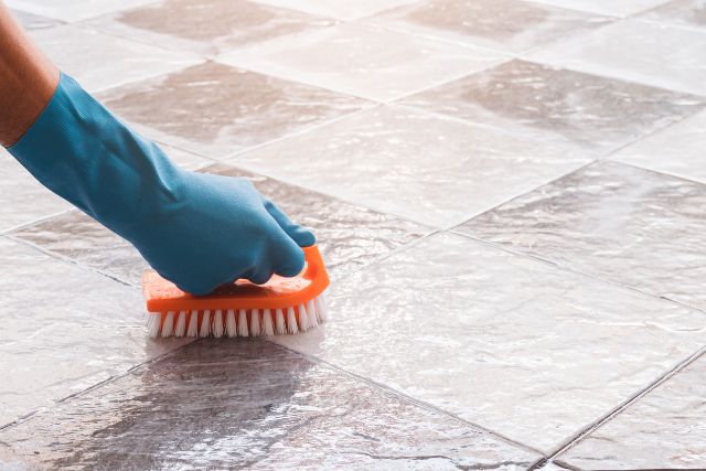 A hand brushing floor tiles.