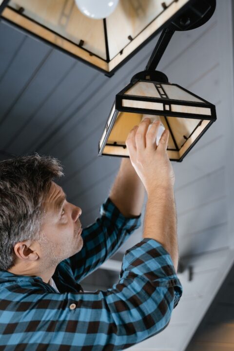 A man doing a DIY installation on his light bulbs.