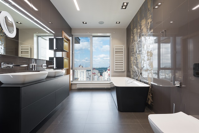 Interior of modern bathroom with bathtub and big windows.