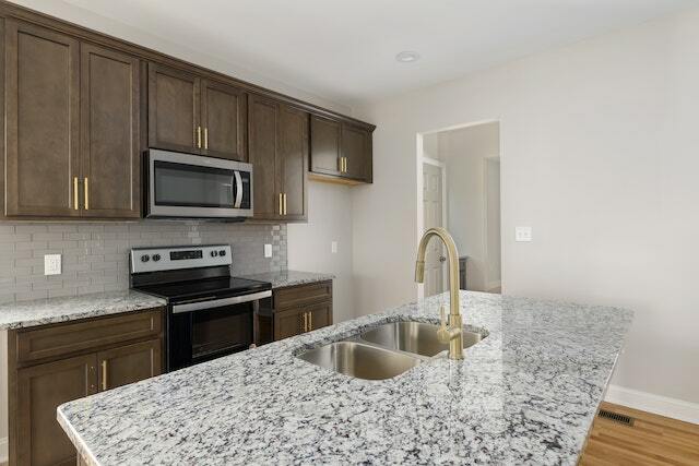 Stainless steel gold faucet on a white & black marble kitchen countertop.