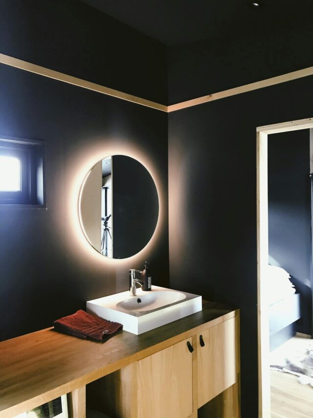 A bathroom vanity with modern mirror that has lighting.