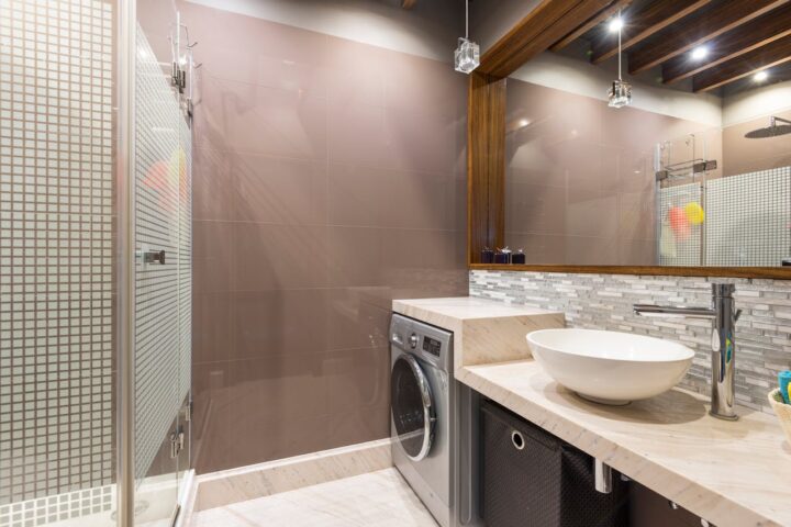 Mirror over a Sink and a Washing Machine and a Shower in a Bathroom.