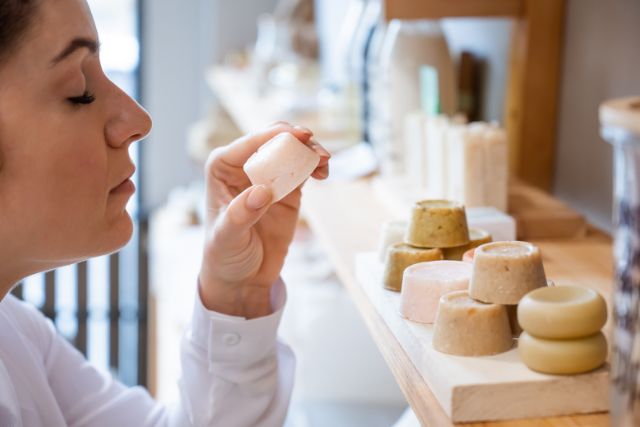 Woman smelling a handmade soap in an eco-friendly store.