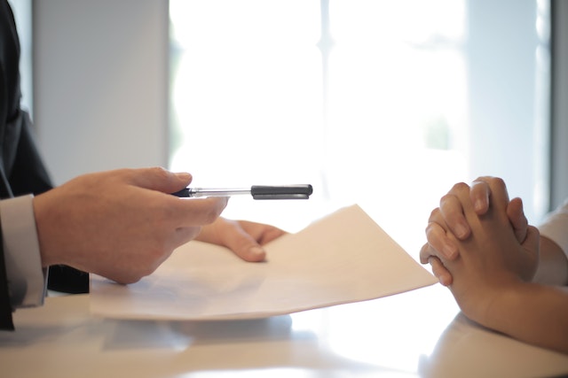 A hand giving some permit forms that needs to be filled in.