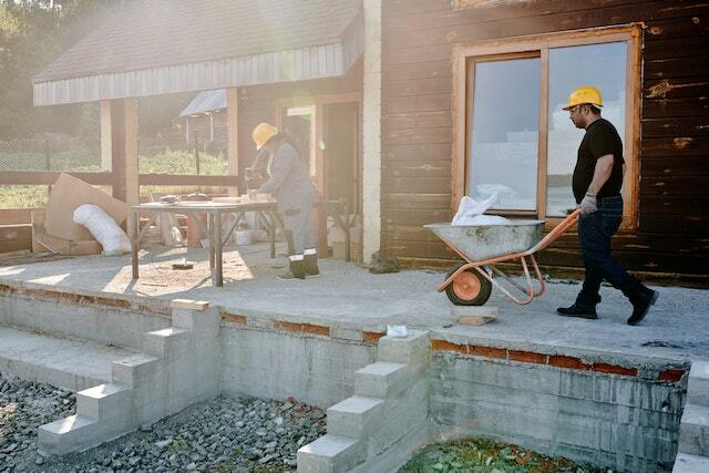 Two construction workers working on a house renovation project.