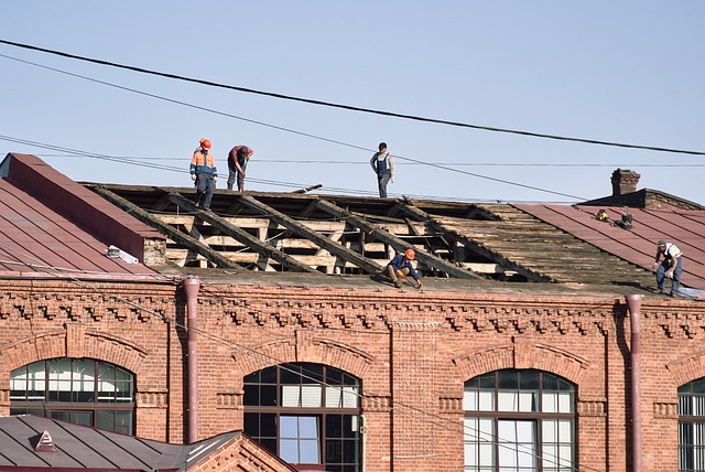 Several worker removes the roof of an old structure.