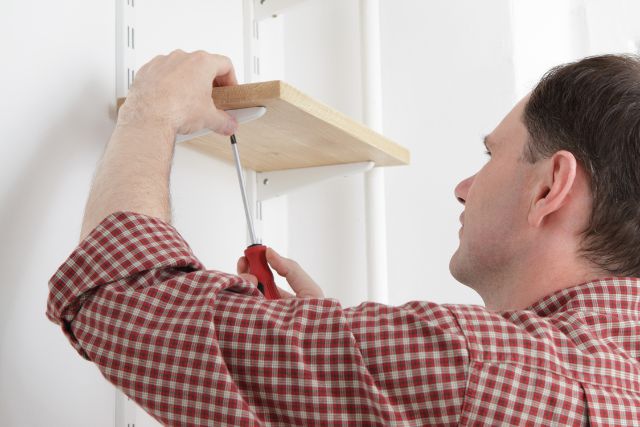 A man installing shelves using brackets.