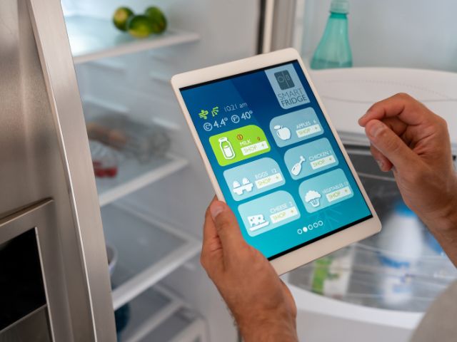 A man controlling its smart refrigerator from a tablet.