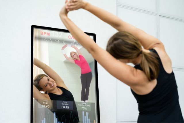 A. woman using a smart mirror for her workout routine.