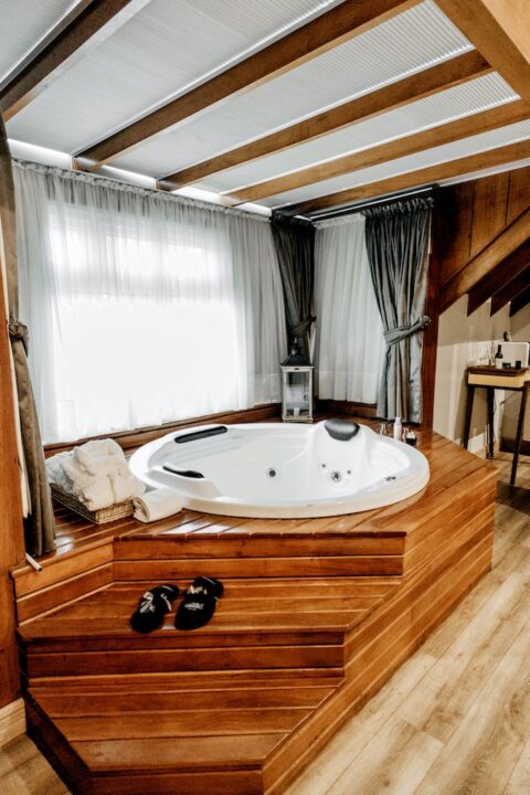 A spa like luxury bathroom with white tub and wooden frame.