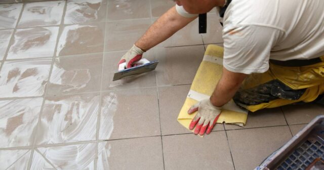 Grouting ceramic tiles on the bathroom floor by a man.