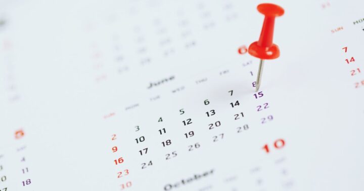 A date is marked using a push pin on a calendar.