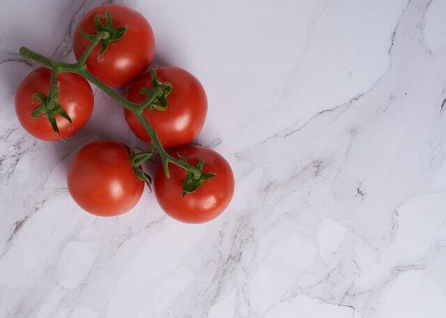 Ripe tomatoes sitting on top of a white granite countertop.