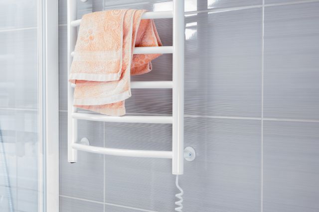 A gray colored bathroom with electric towel warmer rack.