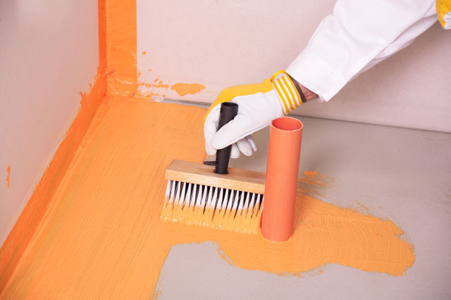 Builder brush applied waterproofing on the floor of bathroom.