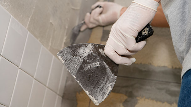 Renovator adding new tiles to wall as part of complete bathroom renovation