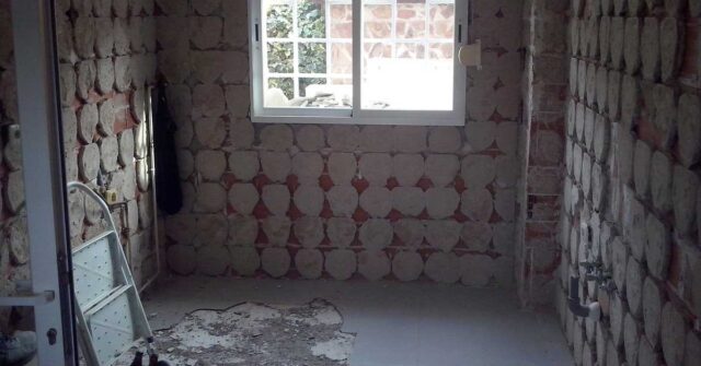 Old bathroom that is stripped of wall and floor tiles.