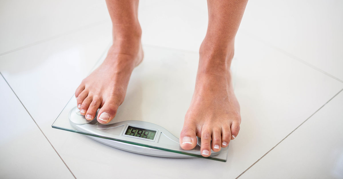 Woman standing with both feet on digital scales.