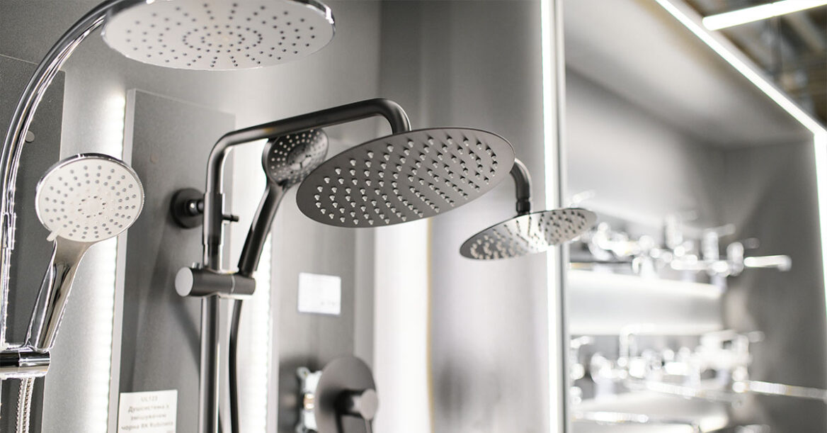 Close-up view of modern rain showerheads and handheld shower fixtures displayed in a showroom.