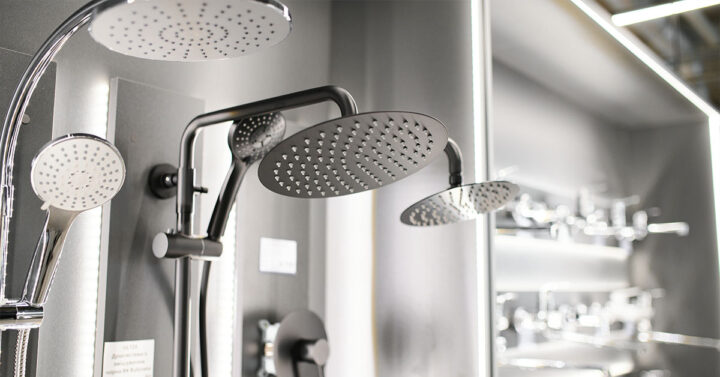 Close-up view of modern rain showerheads and handheld shower fixtures displayed in a showroom.