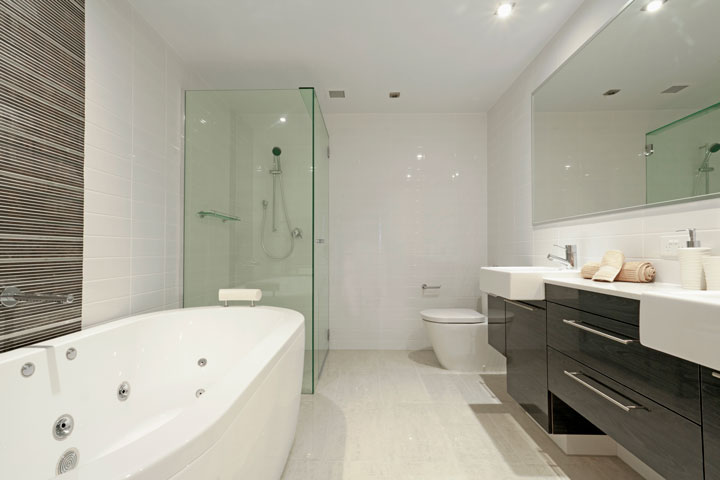 Very stylish bathroom with a spabath, shower, toilet and two sinks.