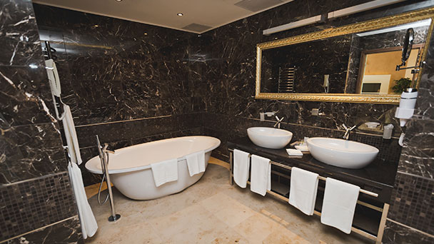 Very stylish black ensuite bathroom with free standing bathtub, his and her sinks and large mirror