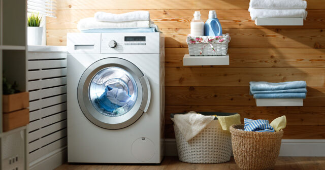 Compact home laundry room with washing machine, shelving and clothes baskets.