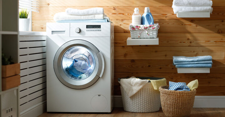 Compact home laundry room with washing machine, shelving and clothes baskets.