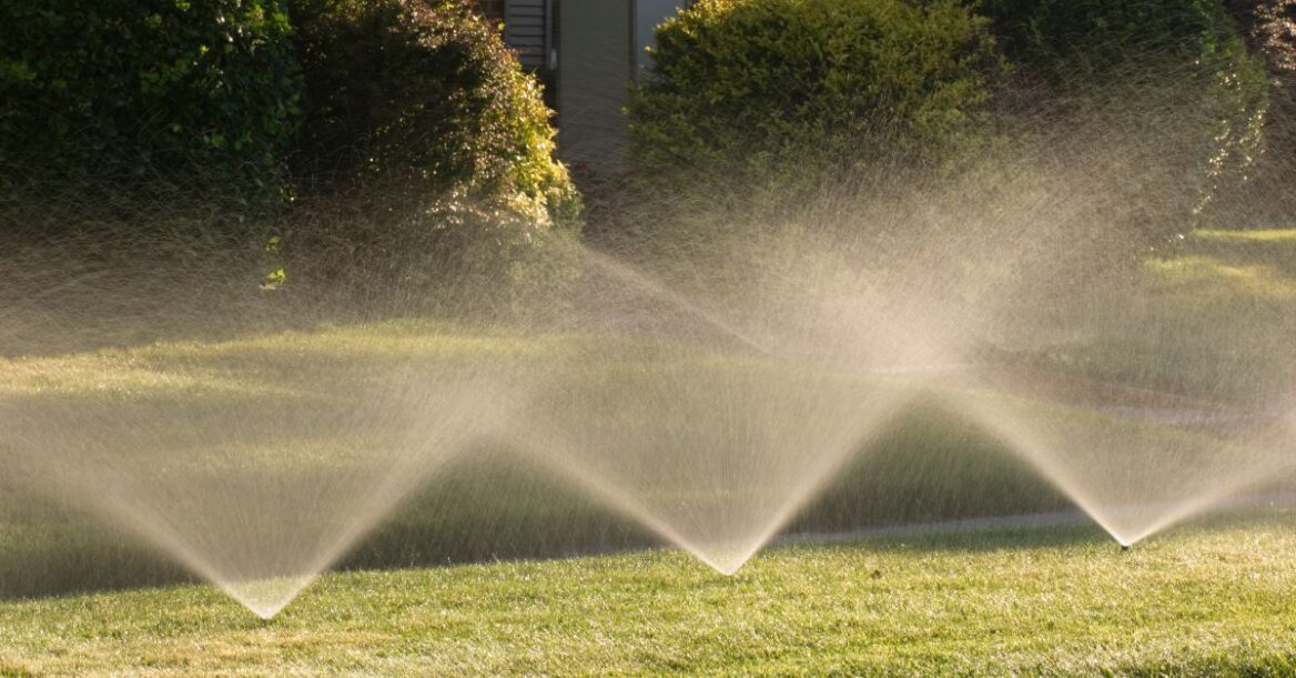 Closeup shot of three lawn sprinklers that are spraying reused water all over the lawn and garden.