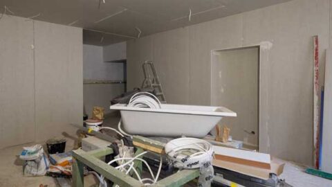 A bathroom undergoing renovation with uninstalled bathtub and other fixtures.
