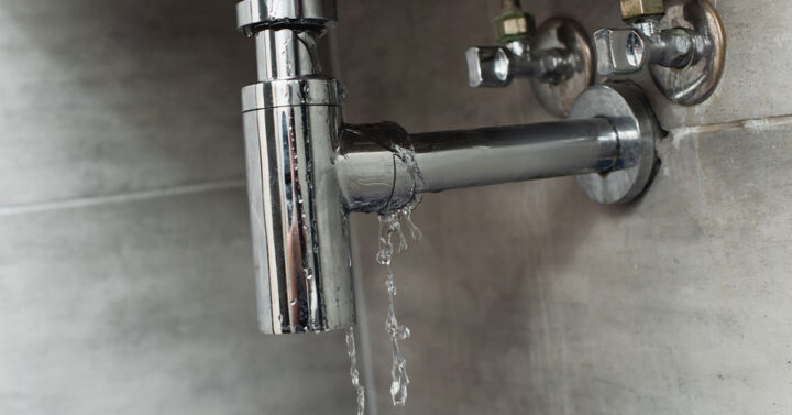 View of leaking pipe with water dripping on it underneath the sink