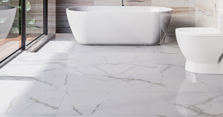 Close-up view of a modern bathroom with glossy white marble-look floor tiles, a freestanding bathtub, and a toilet.