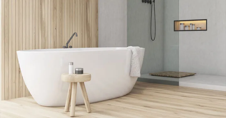 Minimalist bathroom with a white freestanding tub, wood accents, a small stool, and a walk-in shower with a built-in shelf.