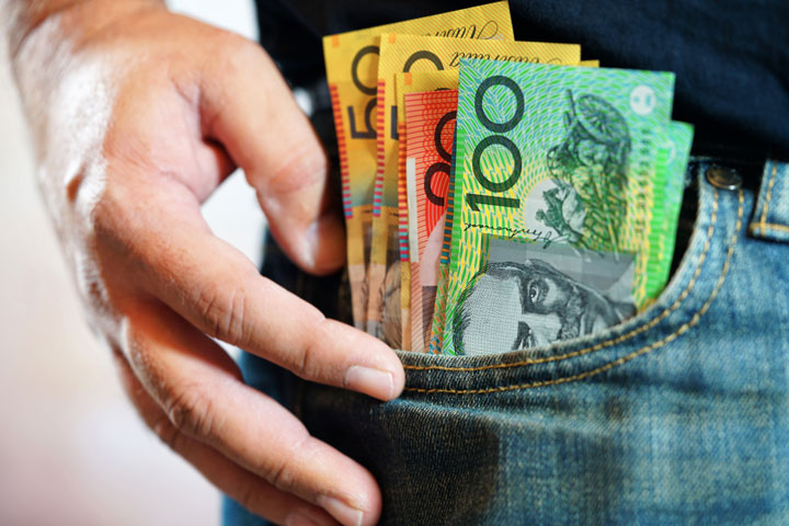 A couple of hundreds, fifty and twenty dollar notes sticking out of mans jeans pocket.