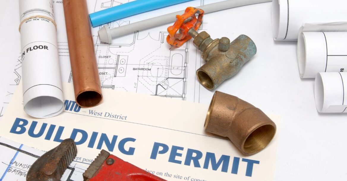Plans and building permit papers with some plumbing parts
