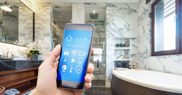 Person holding a phone in a bathroom that is connected to some smart devices