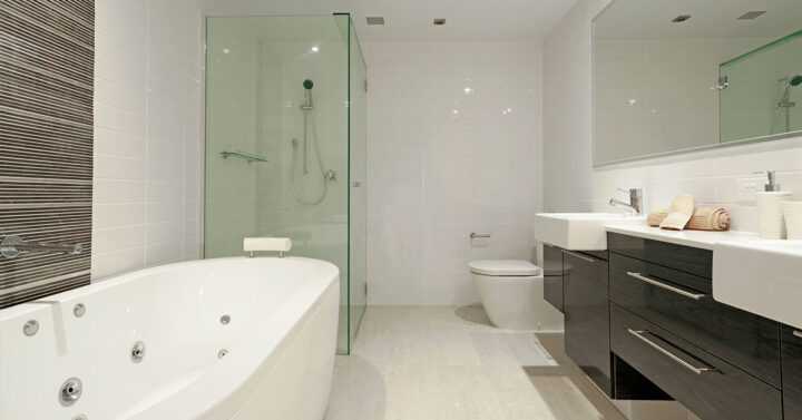 Modern bathroom with a spa tub, glass shower, double sinks, and sleek cabinetry.