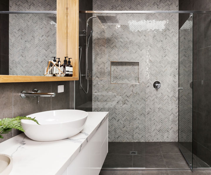Elegant bathroom featuring a large walk-in glass shower with herringbone tile walls, a vessel sink, and modern fixtures.