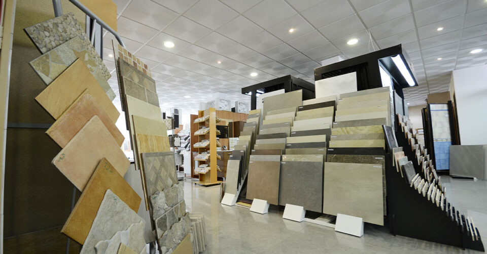 Wide selection of ceramic and stone tile samples displayed on racks in a spacious tile and flooring showroom.