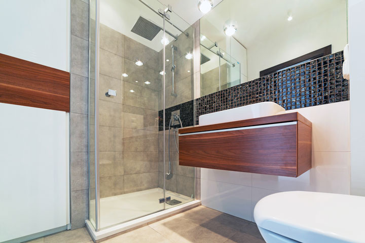 Modern bathroom with a glass-enclosed shower, wood-accented vanity, black mosaic tile backsplash, and large wall mirror.