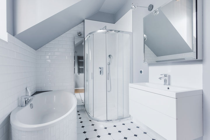 Bright attic bathroom with a corner bathtub, glass-enclosed shower, modern vanity, and white subway tile walls.